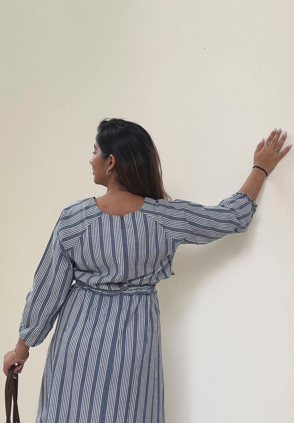 Woman wearing a blue and white striped dress against a plain background